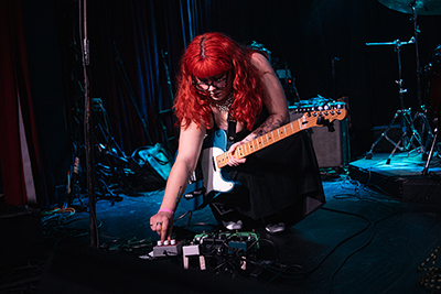 photo of Maya Harrison adjusting guitar pedals
